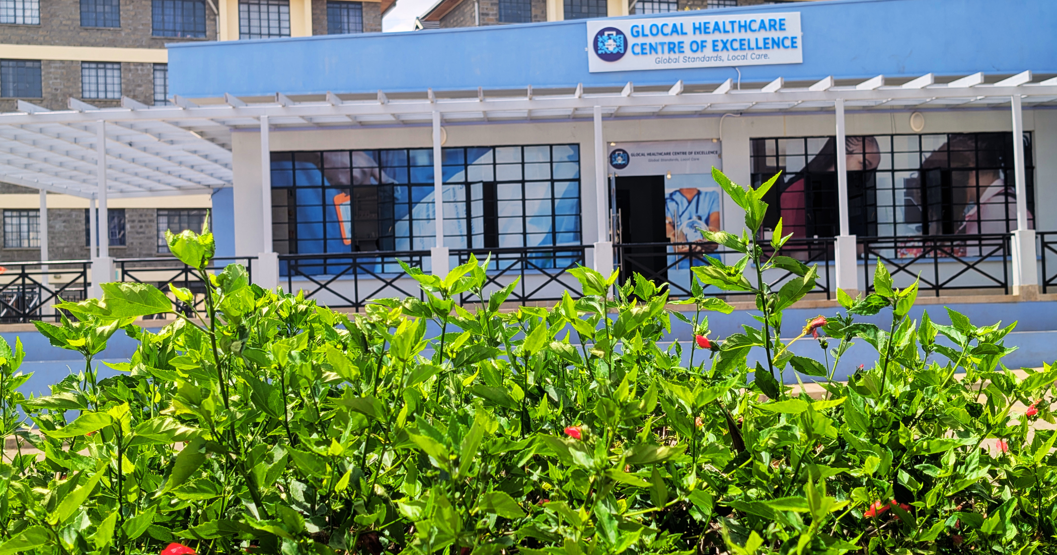 Modern East African hospital exterior with patients and staff